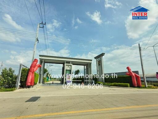 Entrance gate to residential area with large pillars and promotional inflatable figures