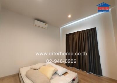 Bedroom with mattress on the floor and air conditioner