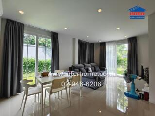 Modern living room with a dining table, large windows, and gray sofas