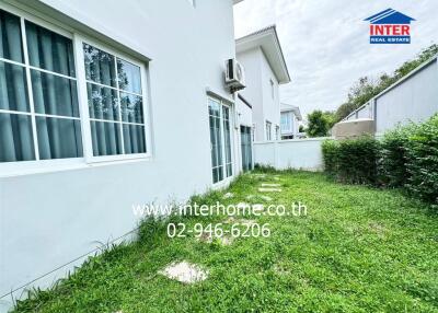 Backyard view of a house with large windows and sliding doors