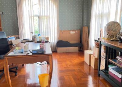 A well-lit home office with wooden floors and a large window.