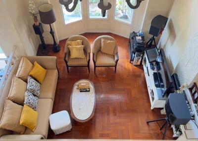 A cozy living room with a beige sofa and two chairs, featuring a coffee table, multiple lamps, and entertainment setup.