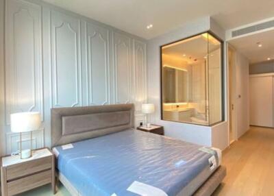 Modern bedroom with elegant design featuring a large window, double bed, nightstands, and ensuite bathroom.