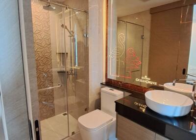 Modern bathroom with glass shower, toilet, and countertop sink