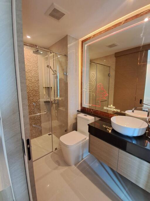 Modern bathroom with glass shower, toilet, and countertop sink