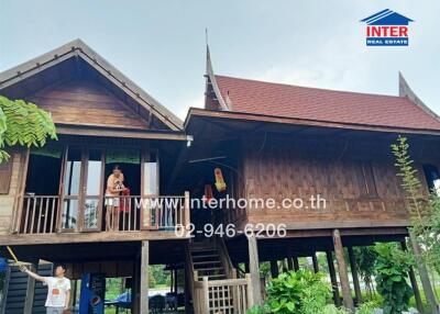 Traditional Thai wooden house with elevated structure and gabled roofs