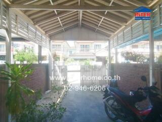 Covered parking area with visible yard and neighborhood view