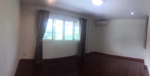 Well-lit bedroom with wooden floor and air conditioning unit