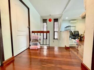 A well-lit hallway area with wooden flooring and adjacent room