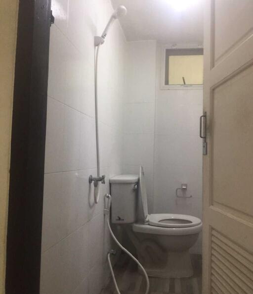 Small bathroom with showerhead, toilet, and window