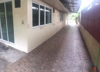 A long exterior corridor with tiled flooring, windows, and sliding doors.