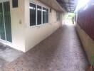 A long exterior corridor with tiled flooring, windows, and sliding doors.