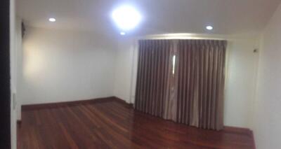 Empty bedroom with wooden flooring and curtains