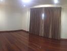 Empty bedroom with wooden floor and large curtains