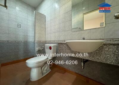 Modern bathroom with tiled walls and floor, featuring a toilet and a wall-mounted sink