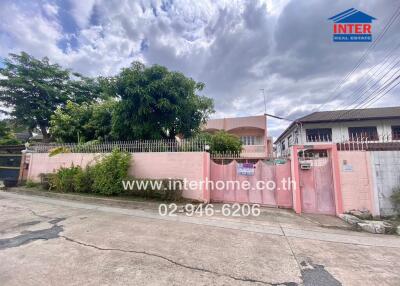 Exterior view of a residential property with a pink wall and gate