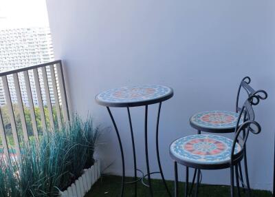 Cozy balcony with bar table and stools, green artificial grass, and decorative plants
