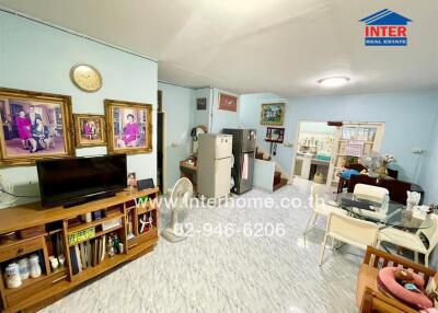 Living area with television, dining table, and visible kitchen.