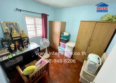 Small bedroom with wooden furniture and various personal items.