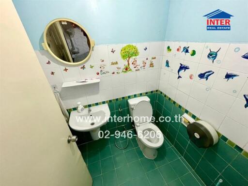 Bathroom with toilet, sink, mirror, and wall decorations