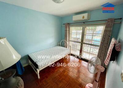 Small bedroom with a single bed, a large window with bars, a standing fan, and air conditioning