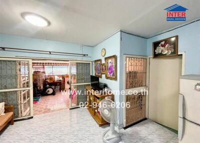 Living room with light blue walls, decorative paintings, and traditional style sliding glass doors leading to another room.