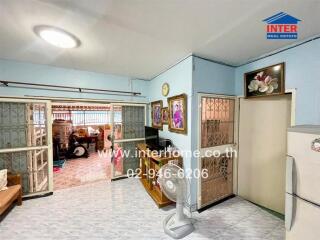 Living room with light blue walls, decorative paintings, and traditional style sliding glass doors leading to another room.