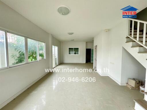 Spacious living room with large windows and staircase