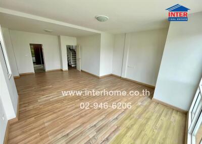 Spacious living room with wooden flooring and white walls.