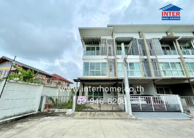 Front view of a modern multi-story residential building with a gated entrance and driveway