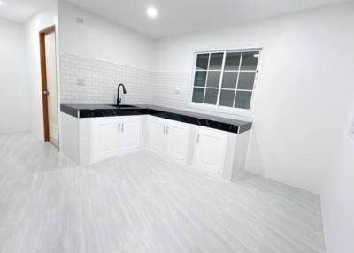 Bright and modern kitchen with white cabinetry and black countertops.