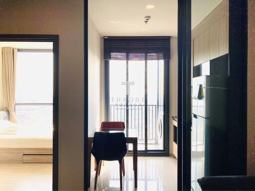 View of a modern apartment showing a dining table, balcony, bedroom, and kitchen.