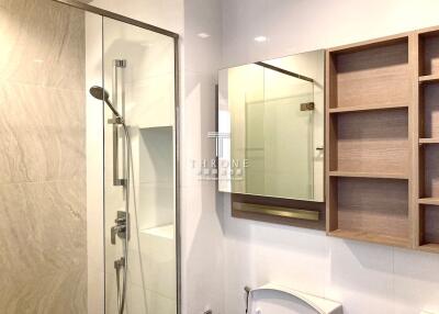 Modern bathroom with a shower, mirror, and wooden shelving