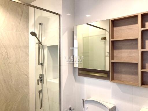 Modern bathroom with a shower, mirror, and wooden shelving