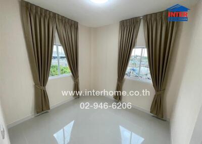 Small unfurnished bedroom with two windows and brown curtains