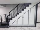 Modern staircase with sleek black railing and white storage cabinets beneath