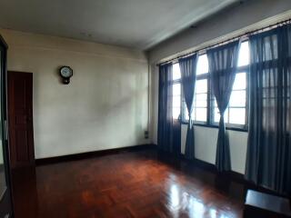 Bright empty bedroom with wooden floor and large windows