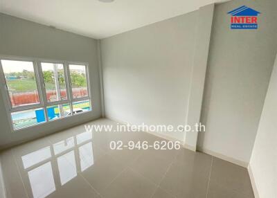 Empty bedroom with tiled floor, large window, and white walls