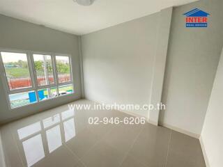 Empty bedroom with tiled floor, large window, and white walls