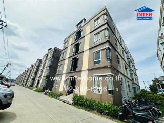 Modern apartment building exterior with parked vehicles and greenery.