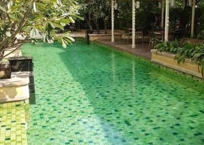 Outdoor swimming pool with green tiles and shaded sitting area