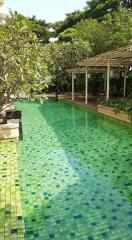 Outdoor swimming pool with green tiles and shaded sitting area