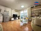 Modern living room with wooden flooring, TV, and balcony access