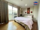 Bedroom with a large bed, wooden floor, and a sliding door to a small balcony