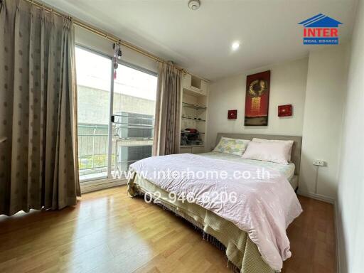 Bedroom with a large bed, wooden floor, and a sliding door to a small balcony