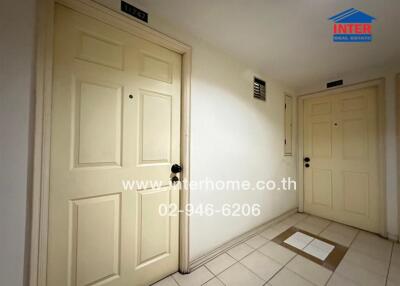 Apartment hallway with two doors and tile flooring