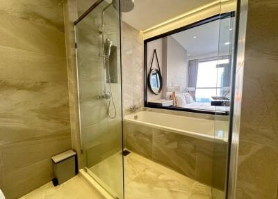 Modern bathroom with glass shower enclosure and bathtub with a view into the bedroom