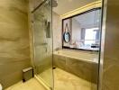 Modern bathroom with glass shower enclosure and bathtub with a view into the bedroom