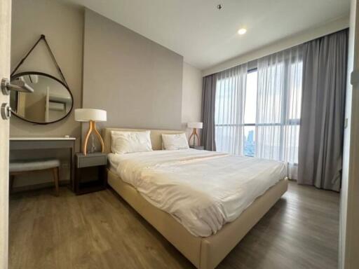 Modern bedroom with a large bed, nightstands, and a window with sheer curtains.