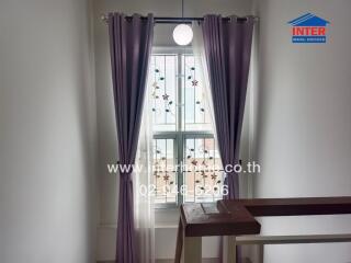 Staircase with a window adorned with floral patterned grills and purple curtains